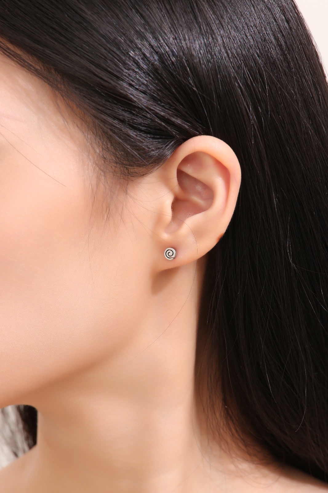 Small Swirl Titanium Studs -solid titanium studs and backs- Feature a small and minimal design on a white woman. 