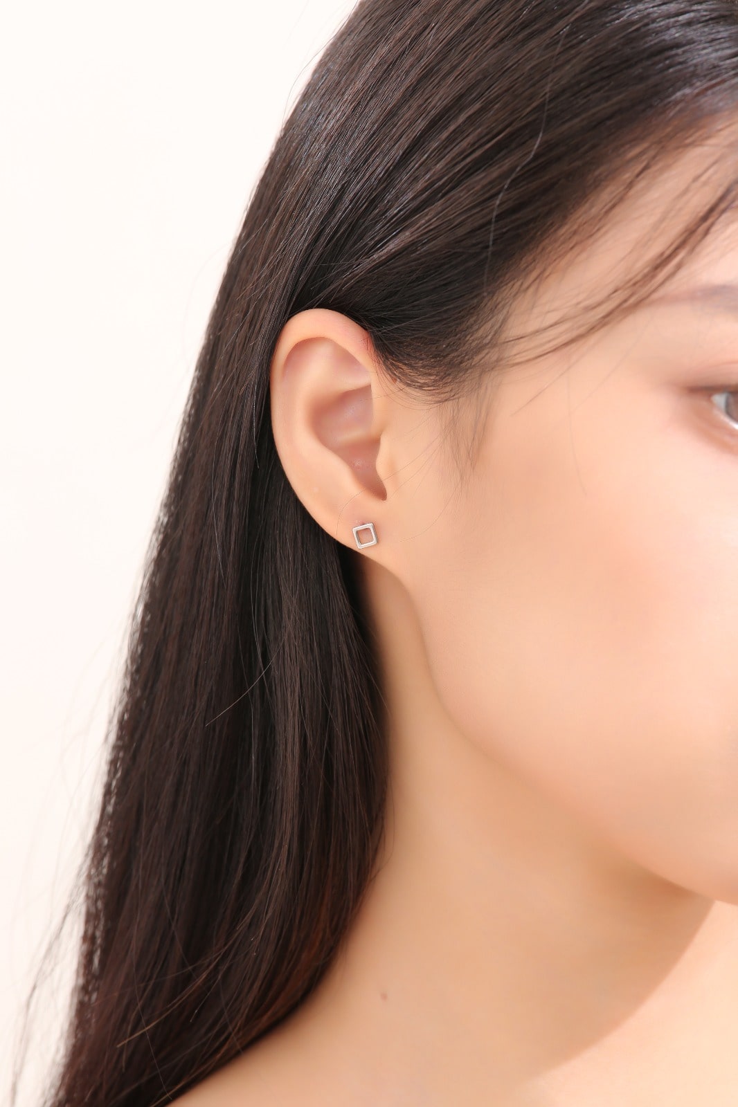 Square Hollow ear studs -solid titanium studs and backs- Feature a small and minimal design on a white woman. 