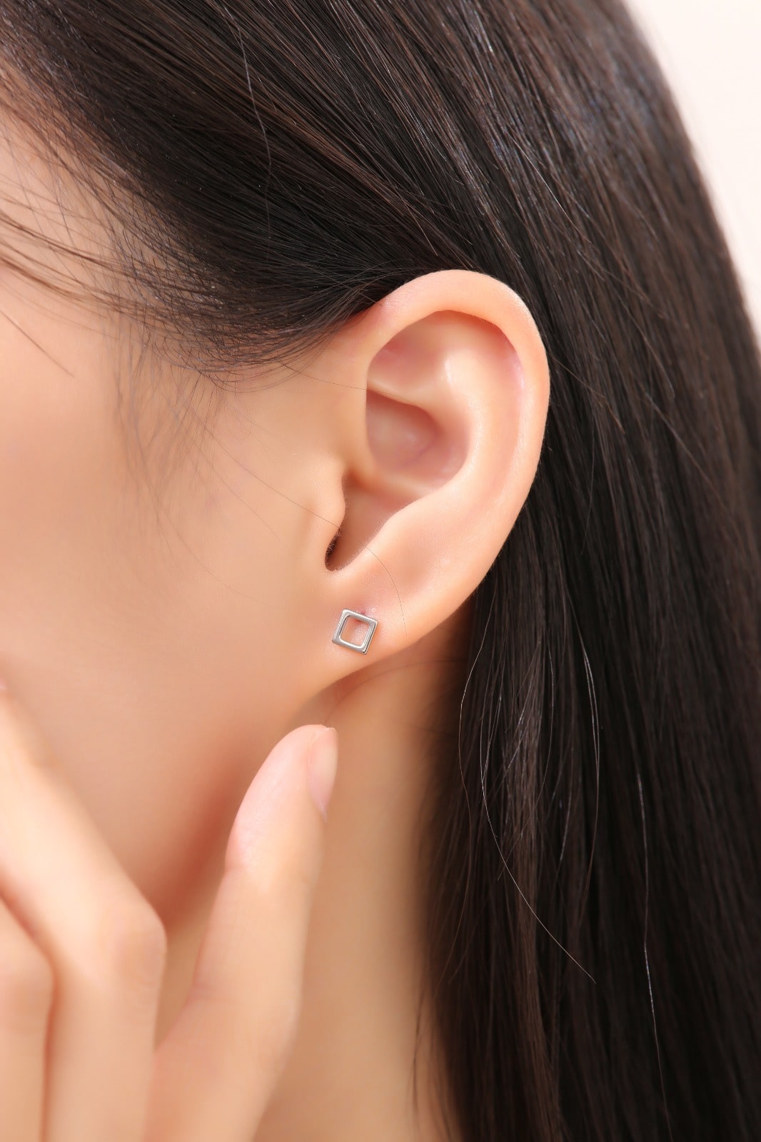 Square Hollow ear studs -solid titanium studs and backs- Feature a small and minimal design on a white woman.  +