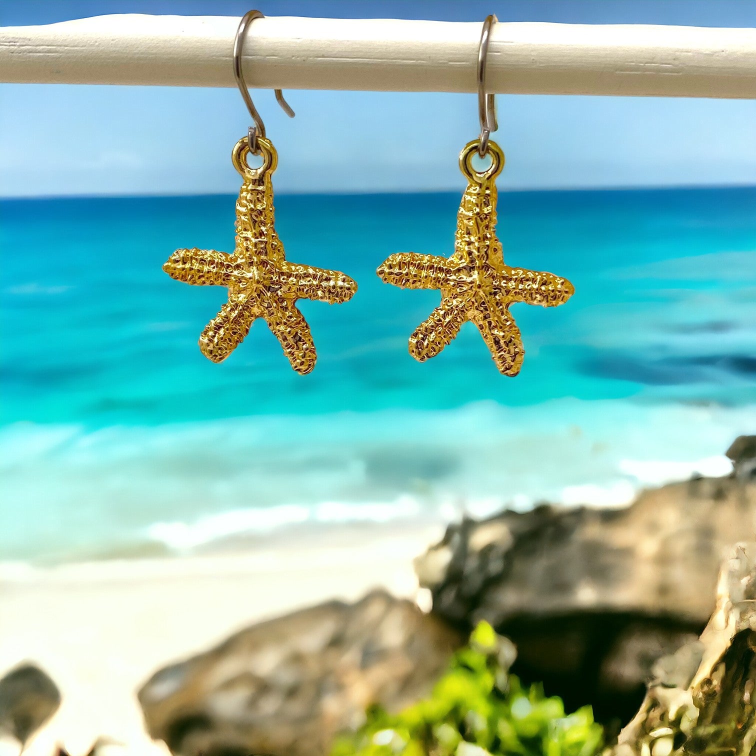 Starfish Charm earrings with a titanium hook on a ocean background