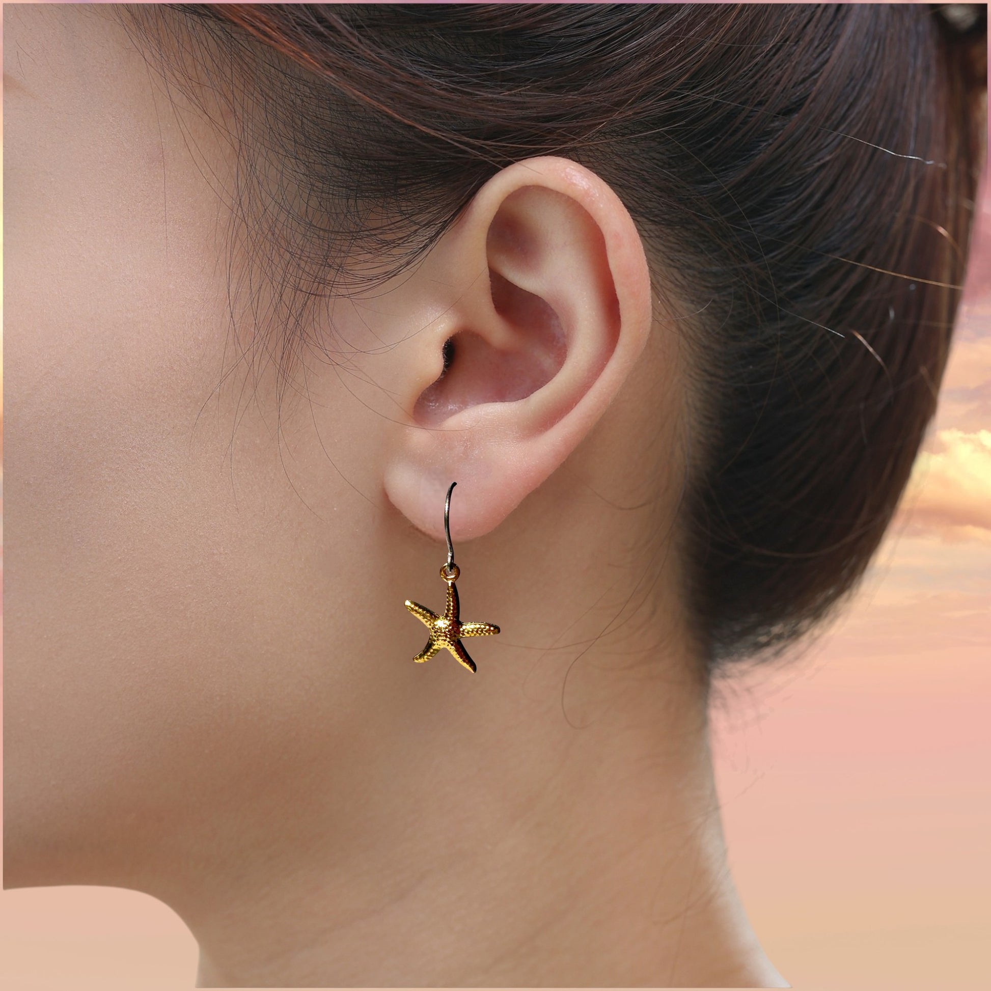Starfish Charm earrings with a titanium hook on a white young woman.