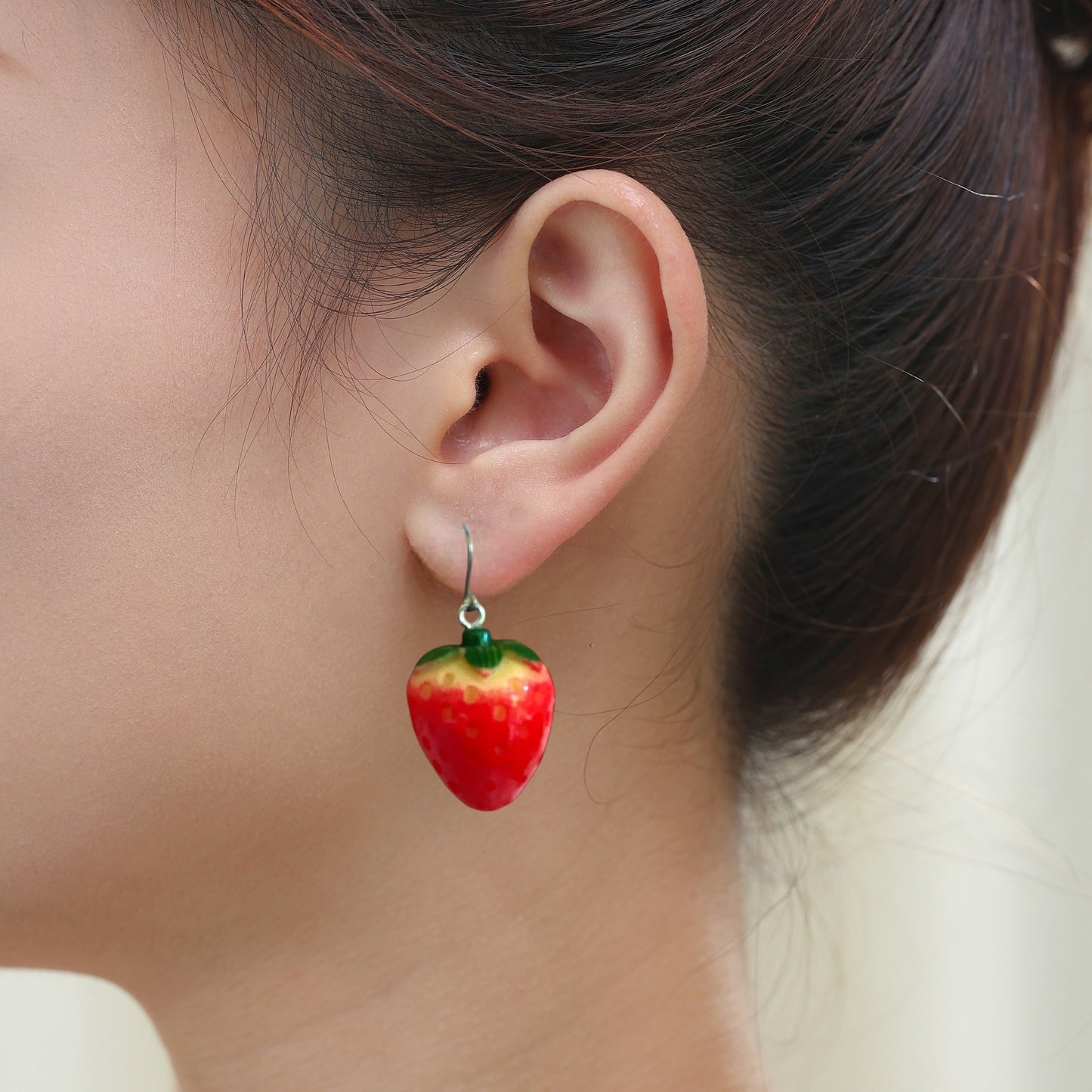 Strawberry earrings with a titanium hook on a white young woman.