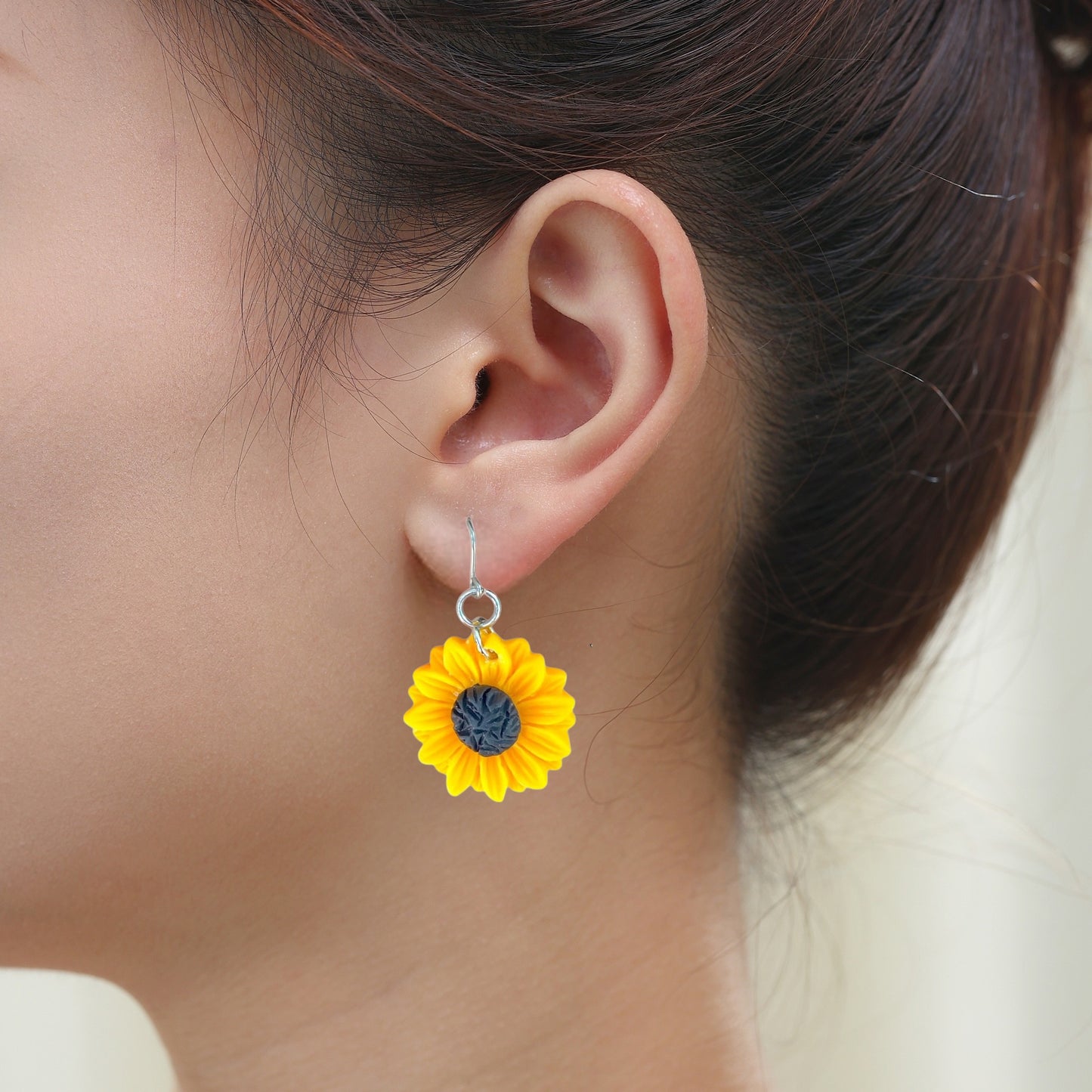 Sunflower earrings with a titanium hook on a white young woman