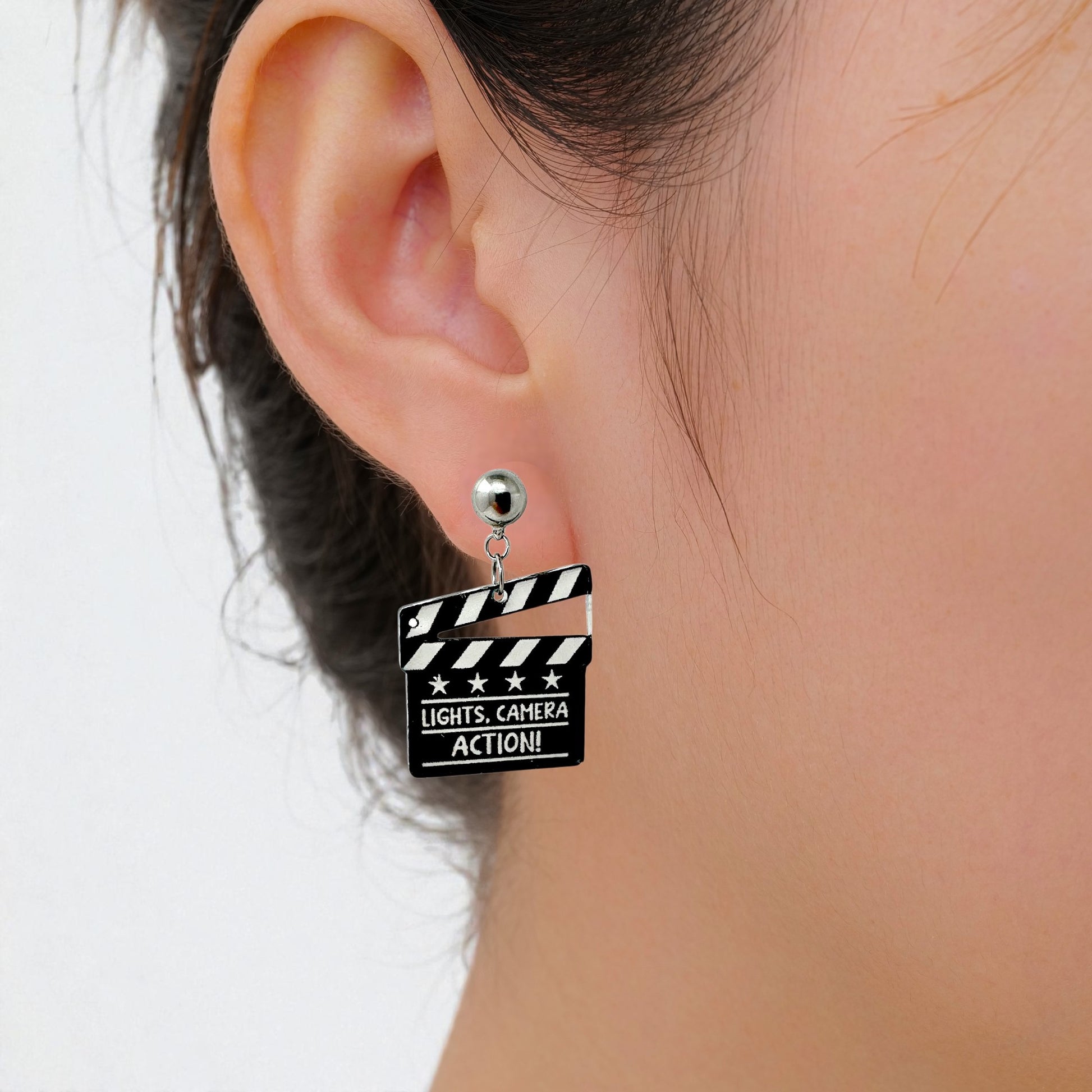 Lights camera action earrings with a titanium magnetic stud on a white woman