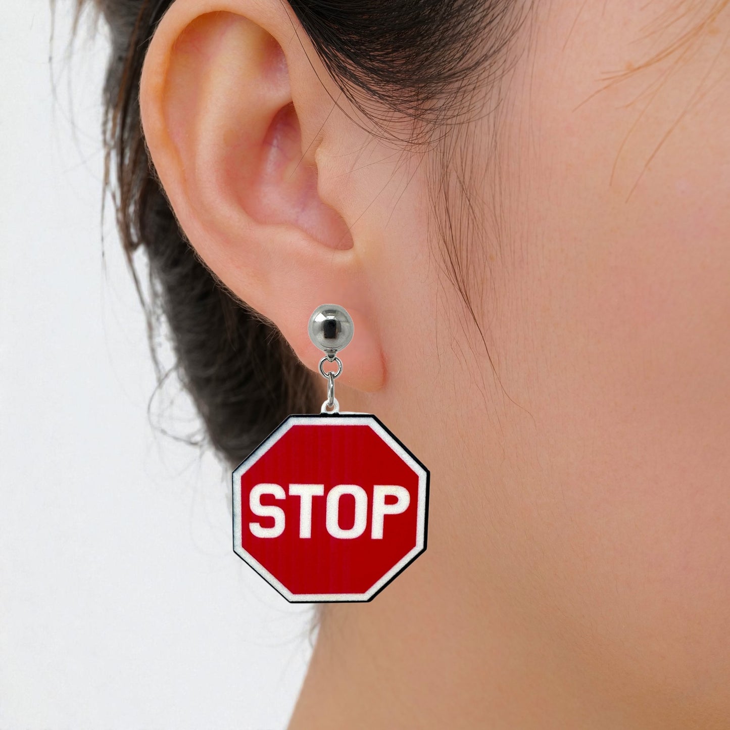 Interchangeable Titanium stop sign earrings pair on a white woman
