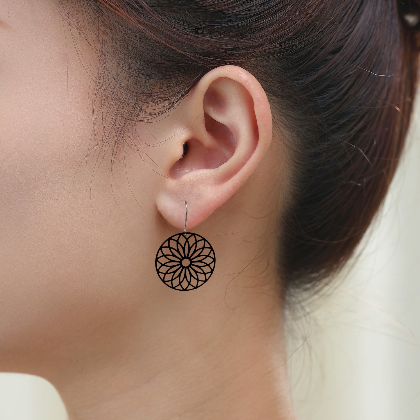 Black Flower Wheel Earrings with titanium hook on a white woman