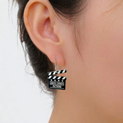 lights camera action titanium earrings on a white woman