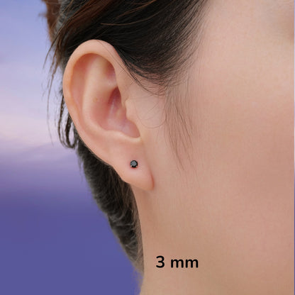 Close-up of an ear wearing a black titanium 3 mm stud earring with a sky background