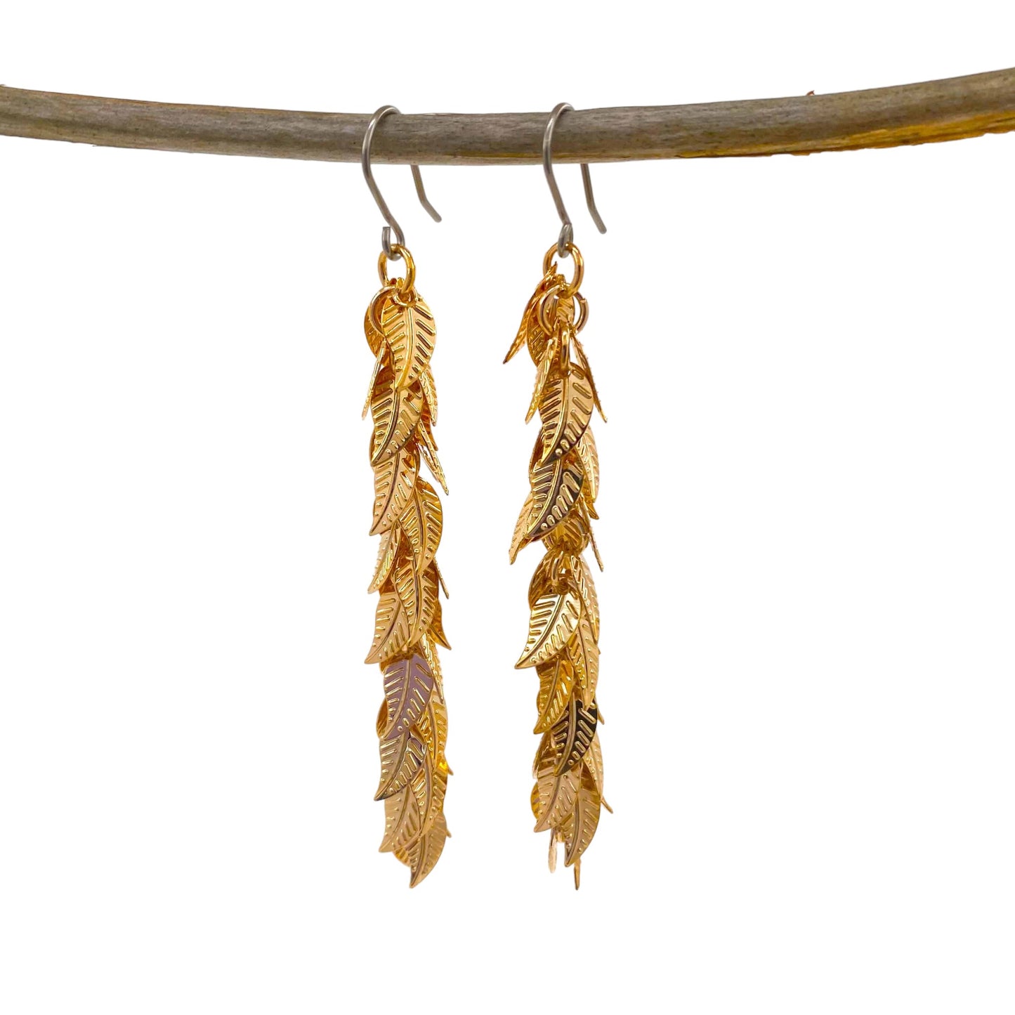 Gold leaves earrings long with a titanium hook on a white background