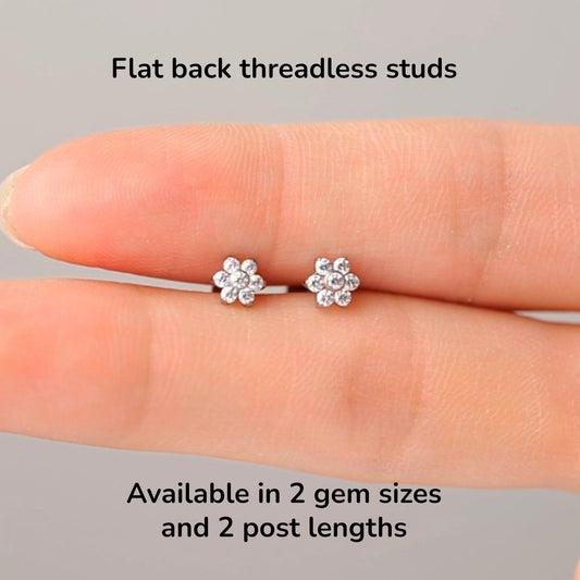 Flower-shaped titanium earrings on a hand with text about flat back threadless studs and size options.