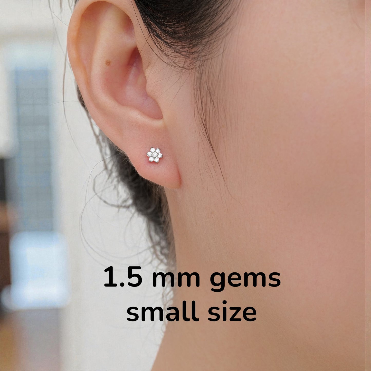 Close-up of an ear wearing a titanium flat back threadless small earring with text indicating '1.5 mm gems small size'.