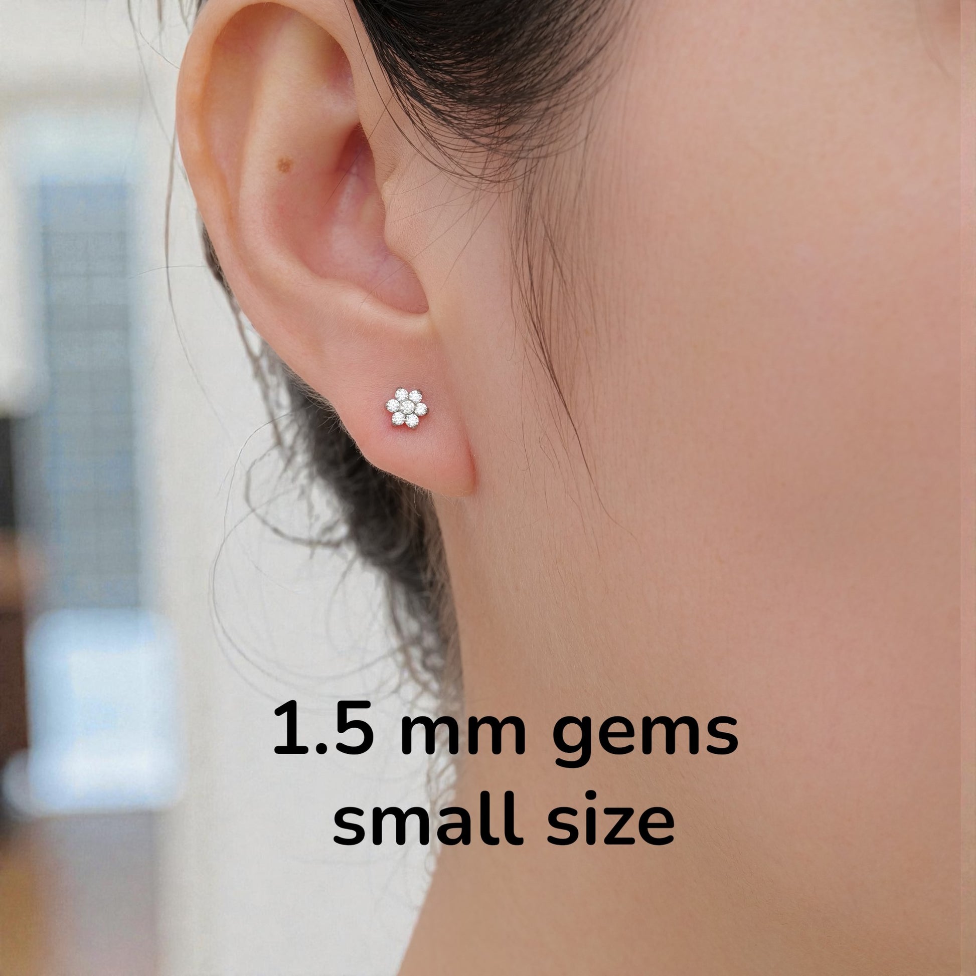 Close-up of an ear wearing a titanium flat back threadless small earring with text indicating '1.5 mm gems small size'.