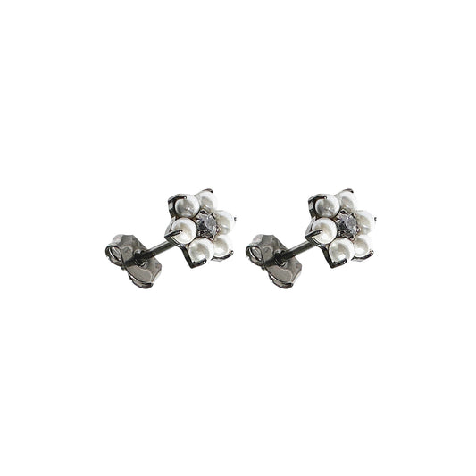 Pair of floral titanium stud earrings with pearls and a gem on a white background