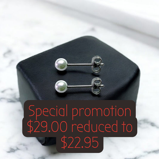 Pearl titanium stud earrings on a black box with a promotional text overlay on a marble background