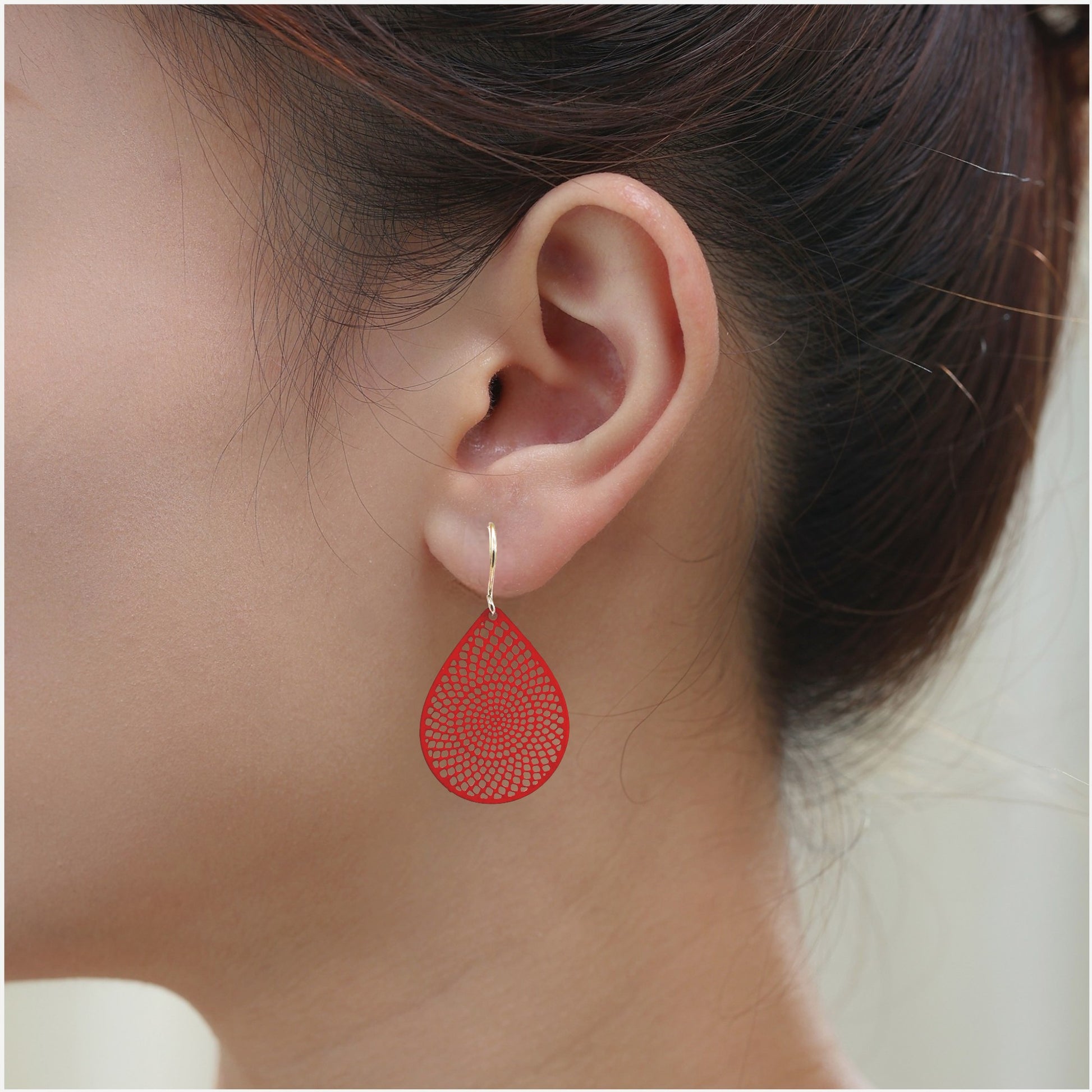 Red teardrop earrings with titanium hook on a white young woman