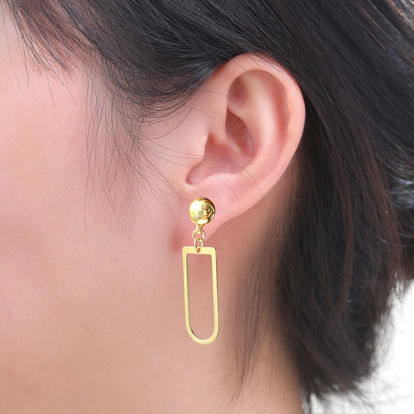 Interchangeable magnetic ti-go gold earring worn on an ear with a neutral background