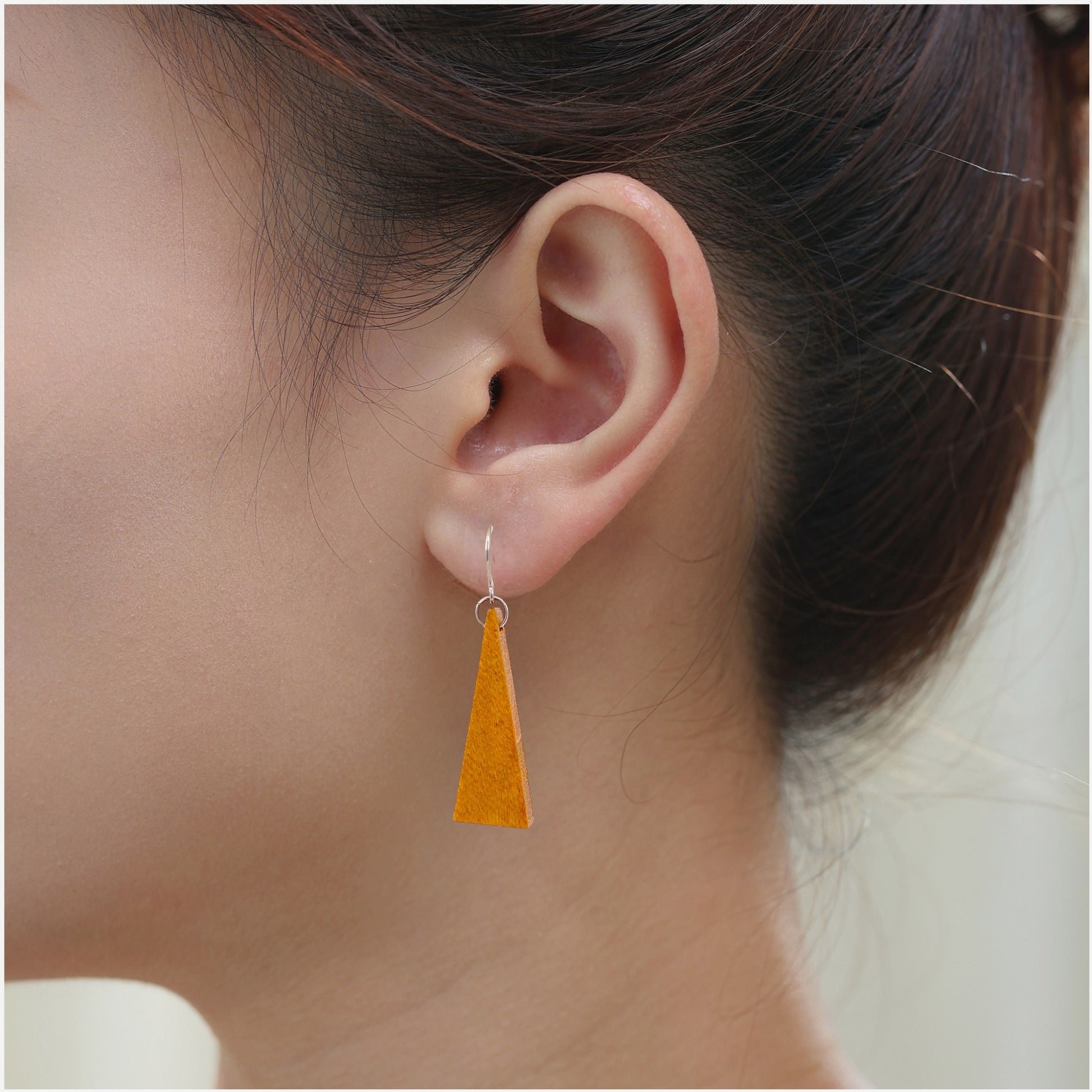 Wooden Triangle Earrings with titanium hook. on a white young woman.