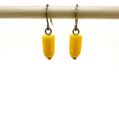 Pencil earrings with a titanium hook on a white background. yellow