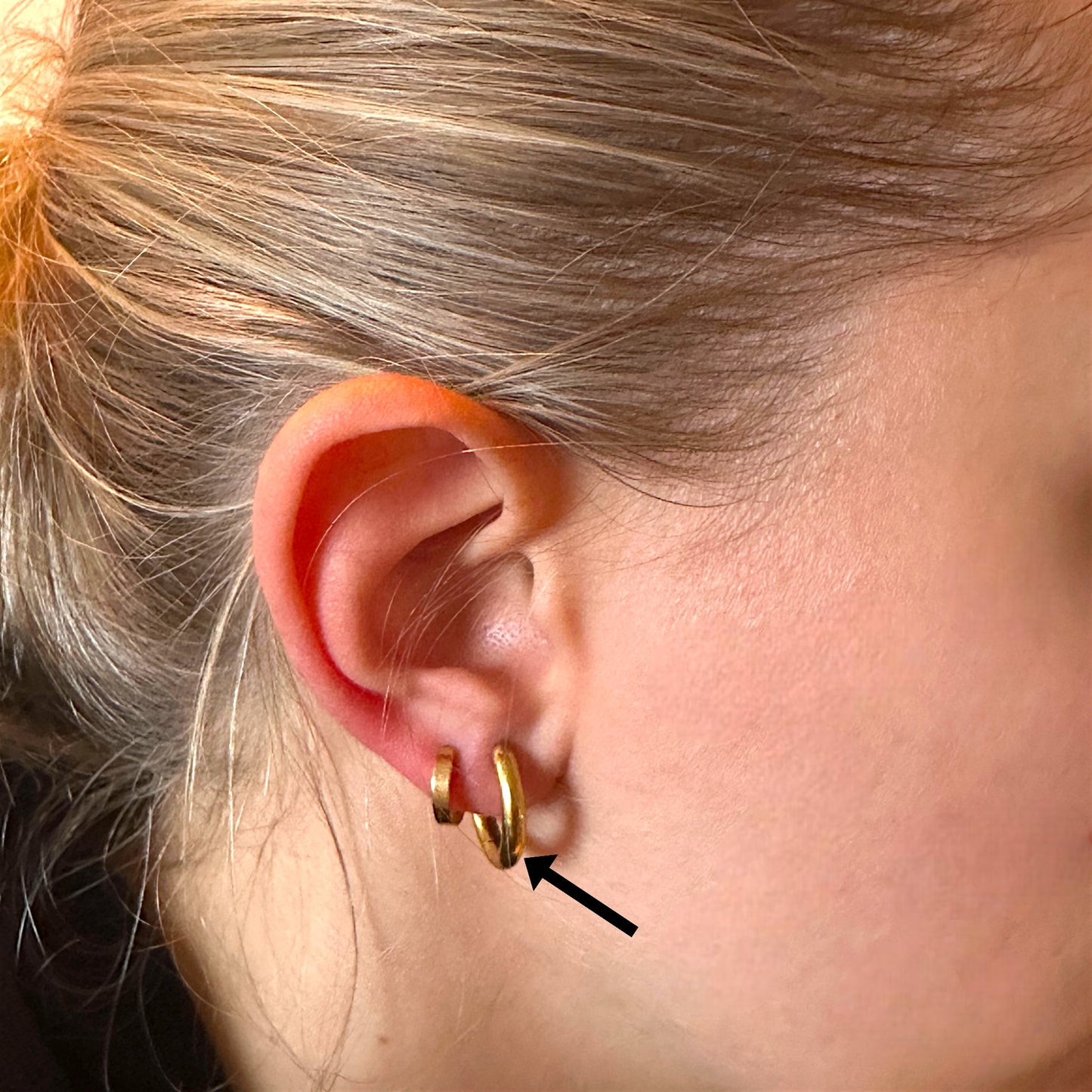 Titanium Gold hoop earring worn by a woman no background