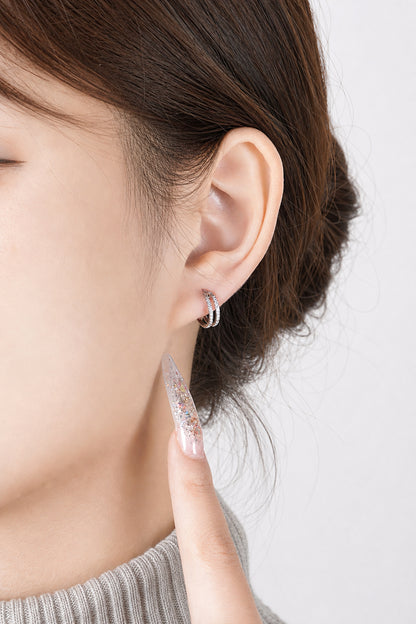 A close-up of a person's ear wearing a titanium small round-shaped hoop earring with diamond gems around both hoops.