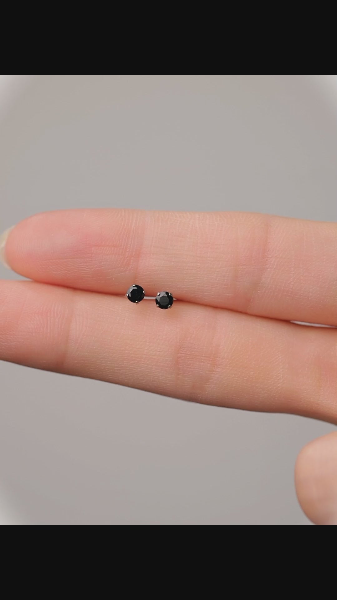 Black titanium earring Close-up of an ear and hand 