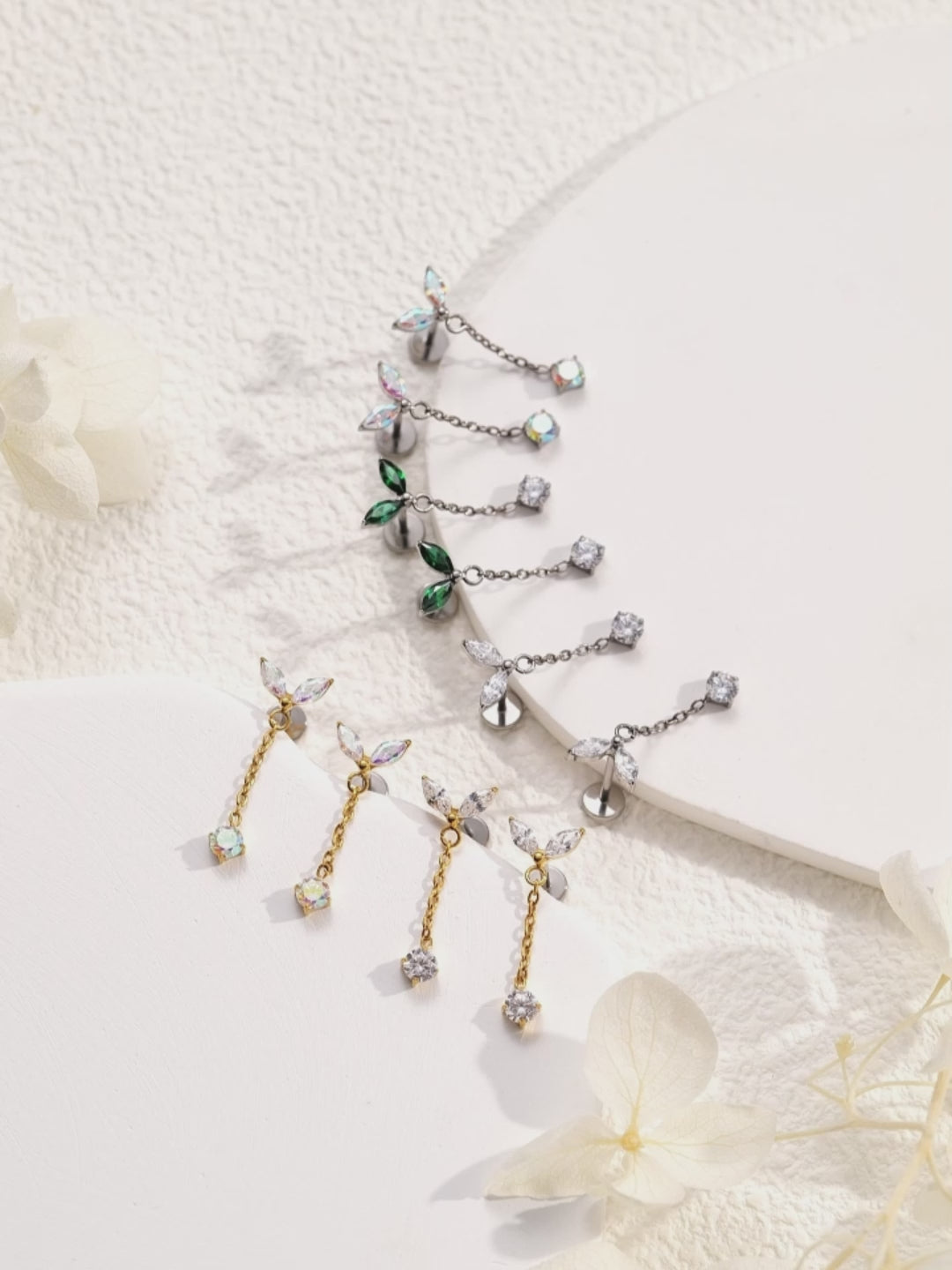 titanium flat back threadless earrings with  leaf like tops and gold chains on a woman avalable in 5 colours