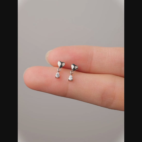 titanium flat back 20 gauge heart studs with hanging gem on fingers and a woman