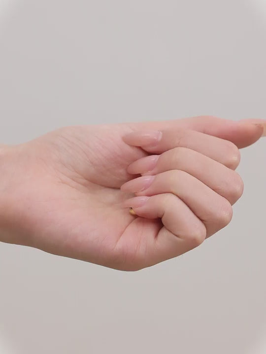 Close-up of an woman wearing a gold titanium hoop earring and in her hand