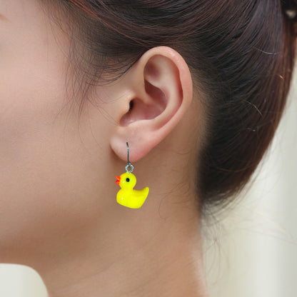 Rubber ducky earrings with a titanium hook on a white young woman.