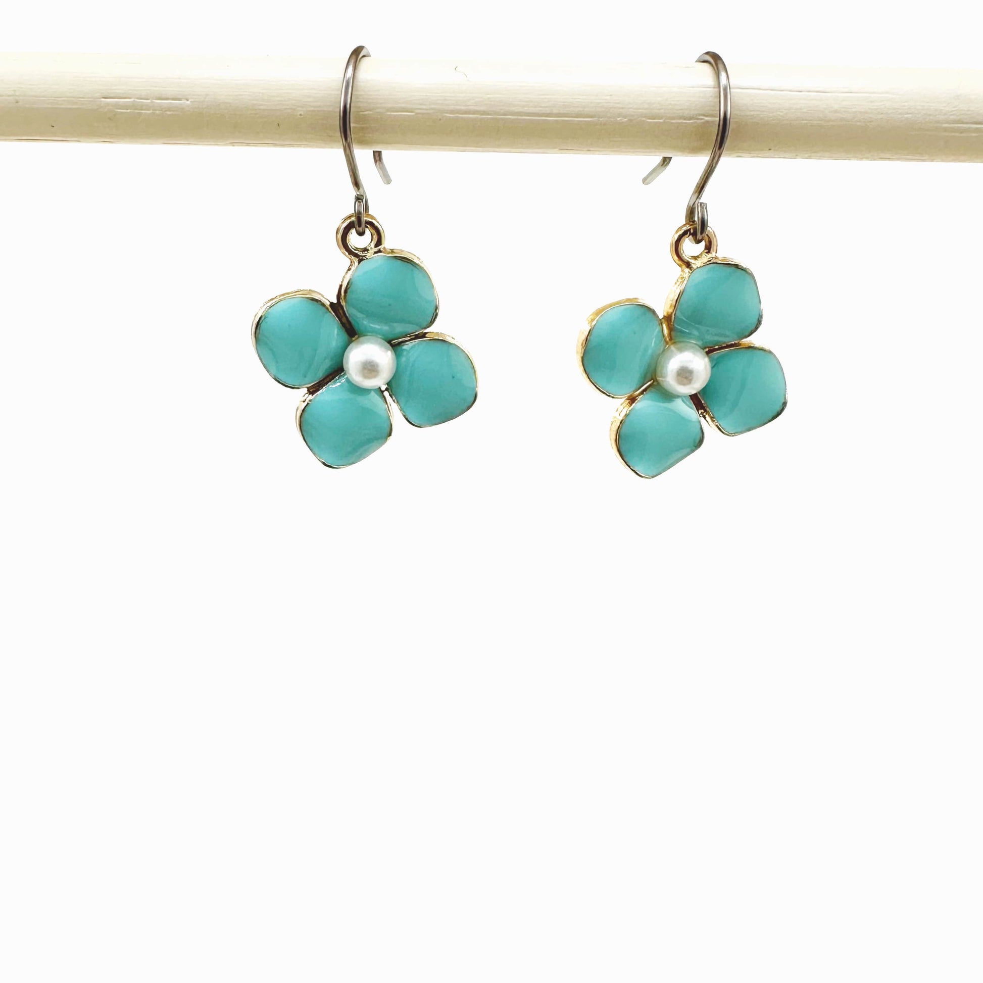 Forget-Me-Not Charm earrings in blue with a pearl in the center and a titanium hook on a white background