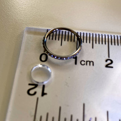 Small Hoop earrings made from titanium. Mini gem studded earring pair, lightweight and durable. On a ruler.