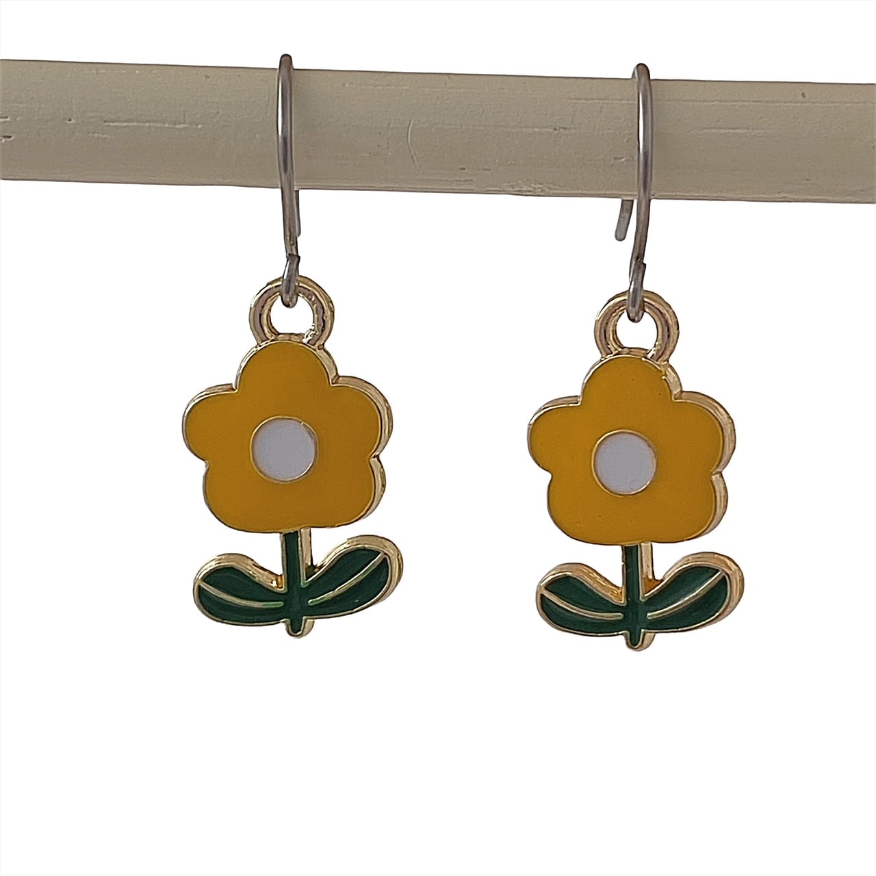 Flower power earrings in yellow with green leaves and a titanium hook on a white background