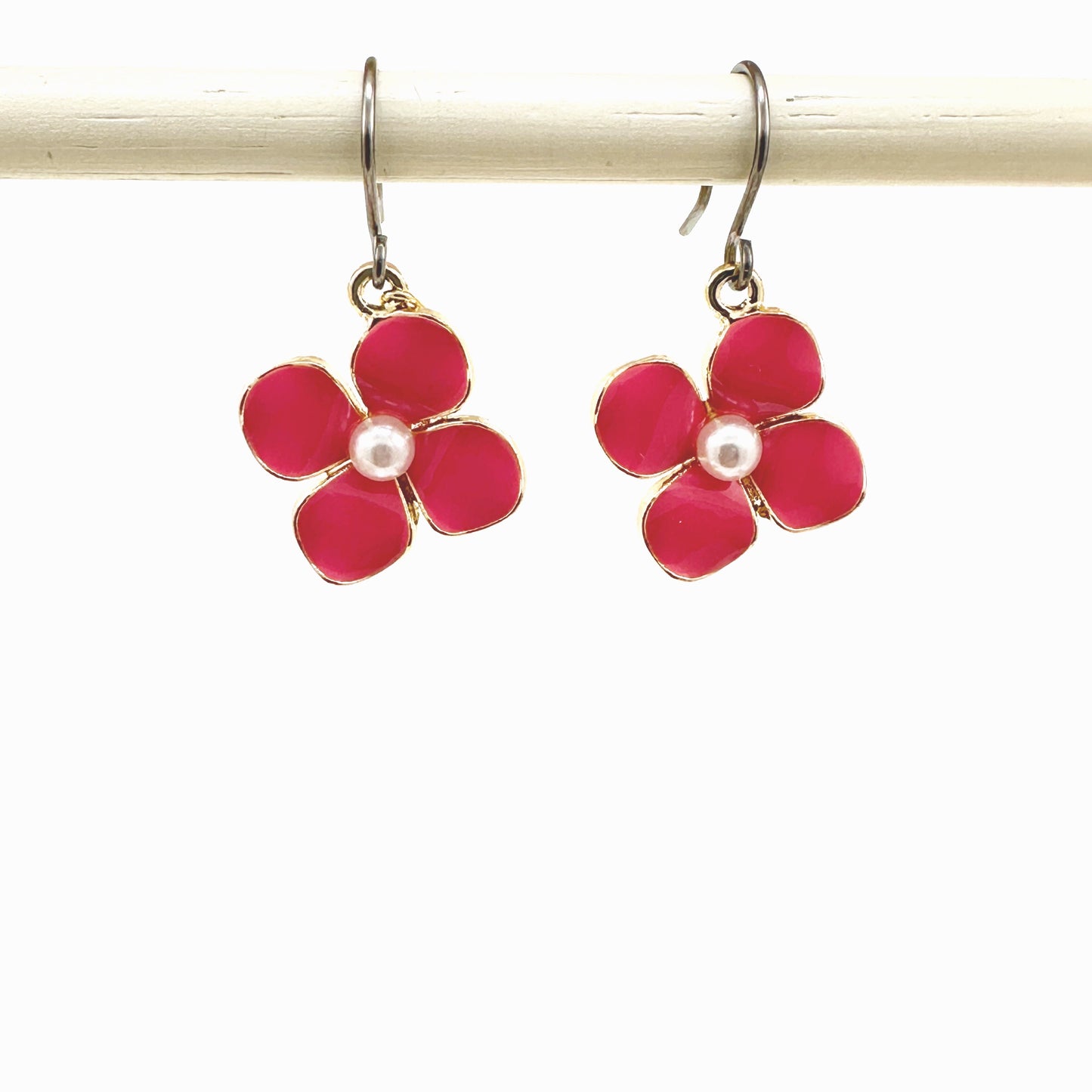 Forget-Me-Not Charm earrings in rose pink with a pearl in the center and a titanium hook on a white background