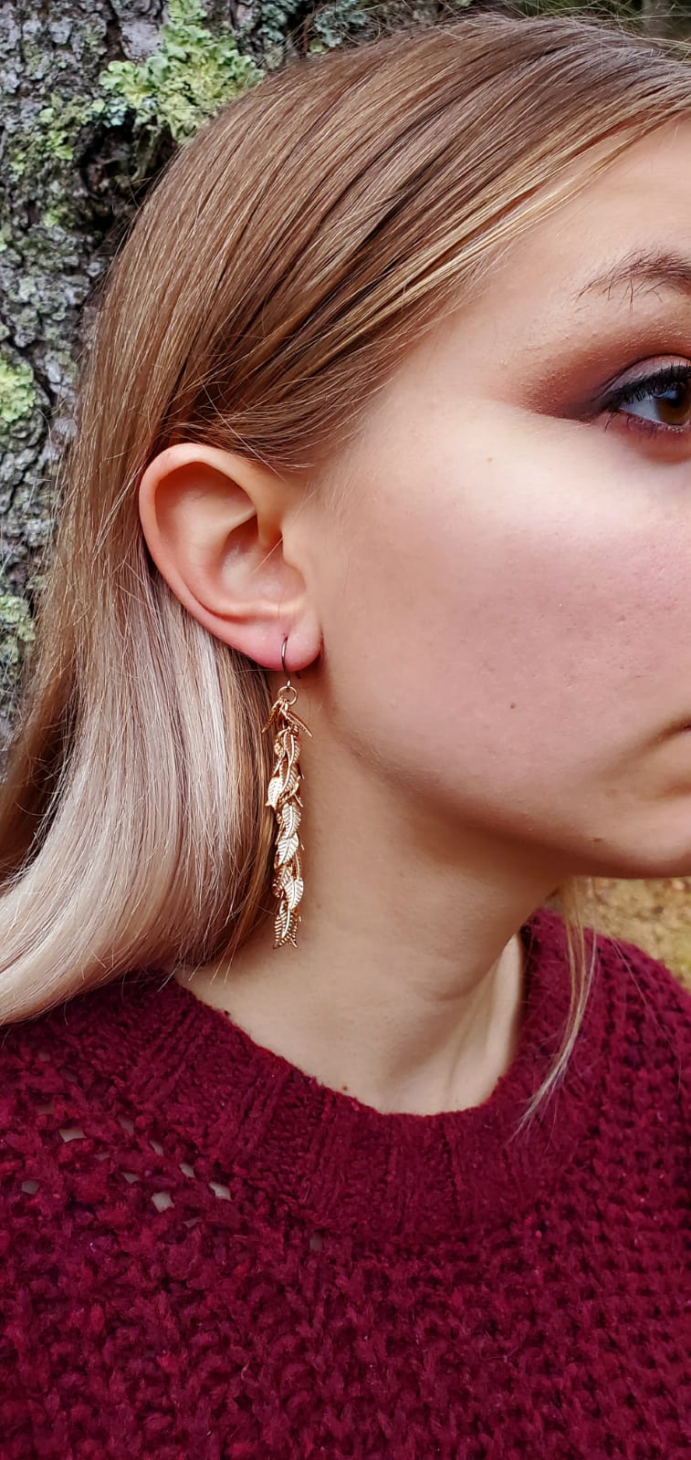 Gold leaves earrings long with a titanium hook on a white young woman. 