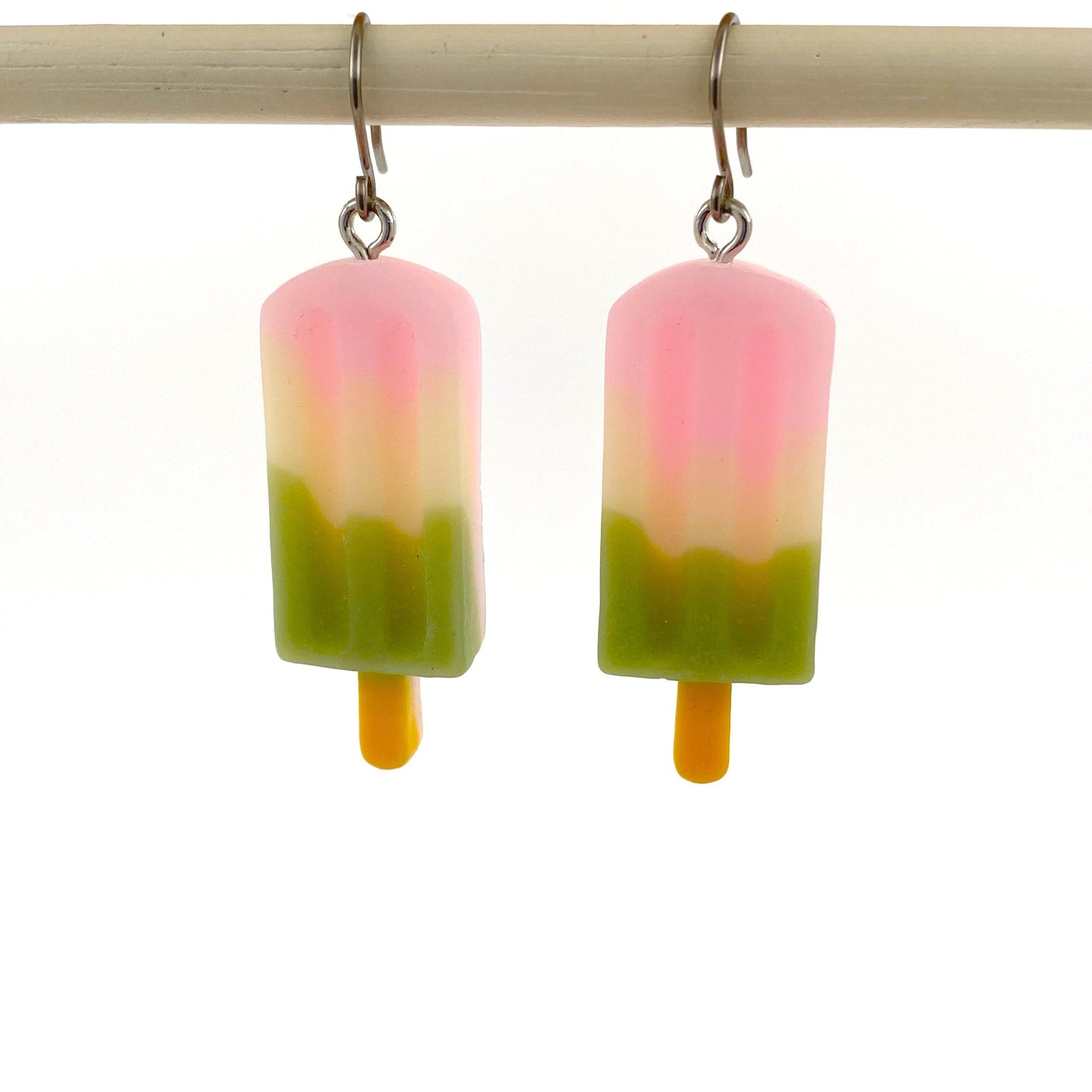 Popsicle earrings with a titanium hook on a white background.  pink green