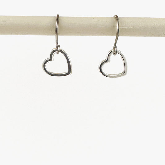 Mini silver heart earrings with a titanium hook on a white background