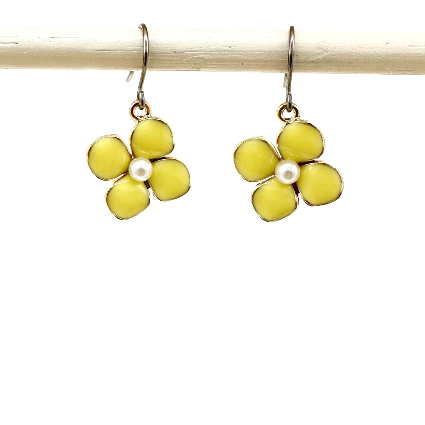 Forget-Me-Not Charm earrings in yellow with a pearl in the center and a titanium hook on a white background