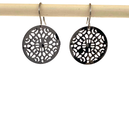 Black geometric disc earrings with a titanium hook on a white background